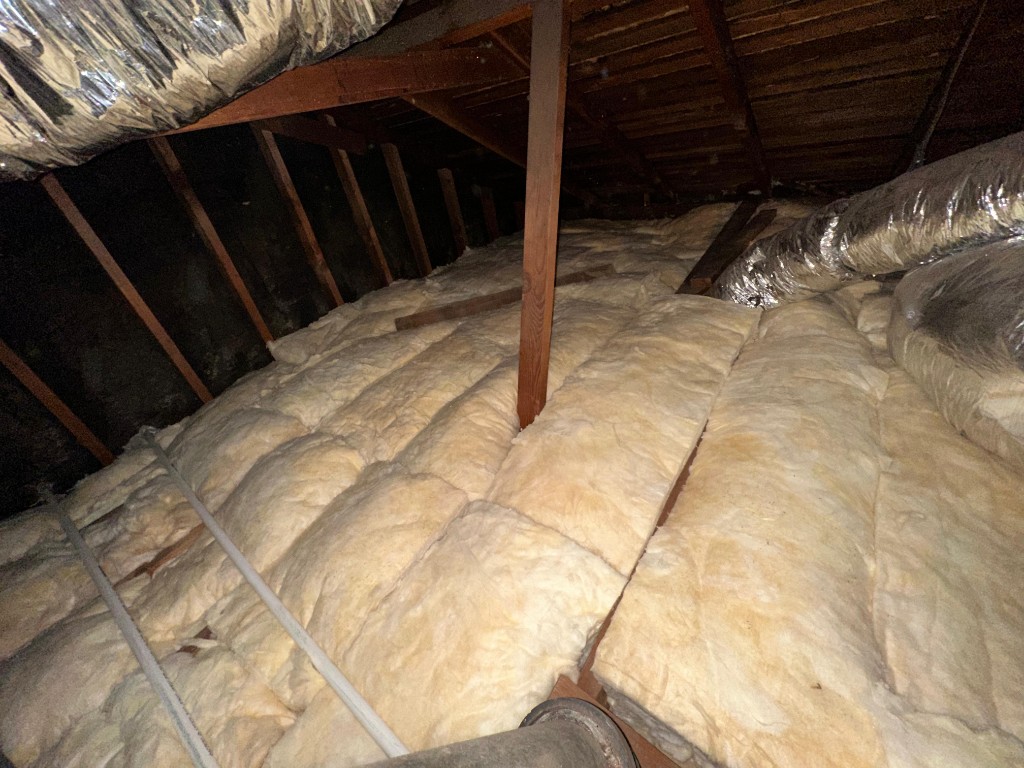 Attic with new fiberglass batt insulation installed to target R-value