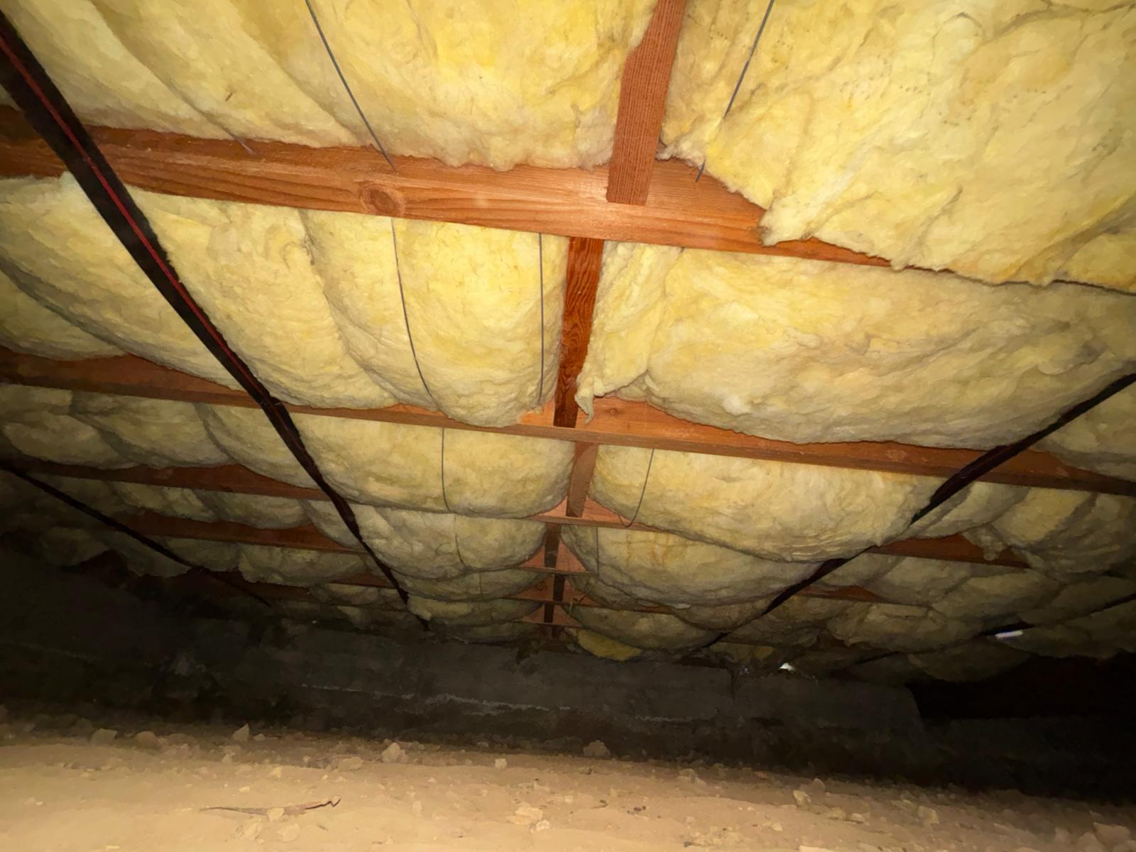 New crawlspace batt insulation secured between floor joists