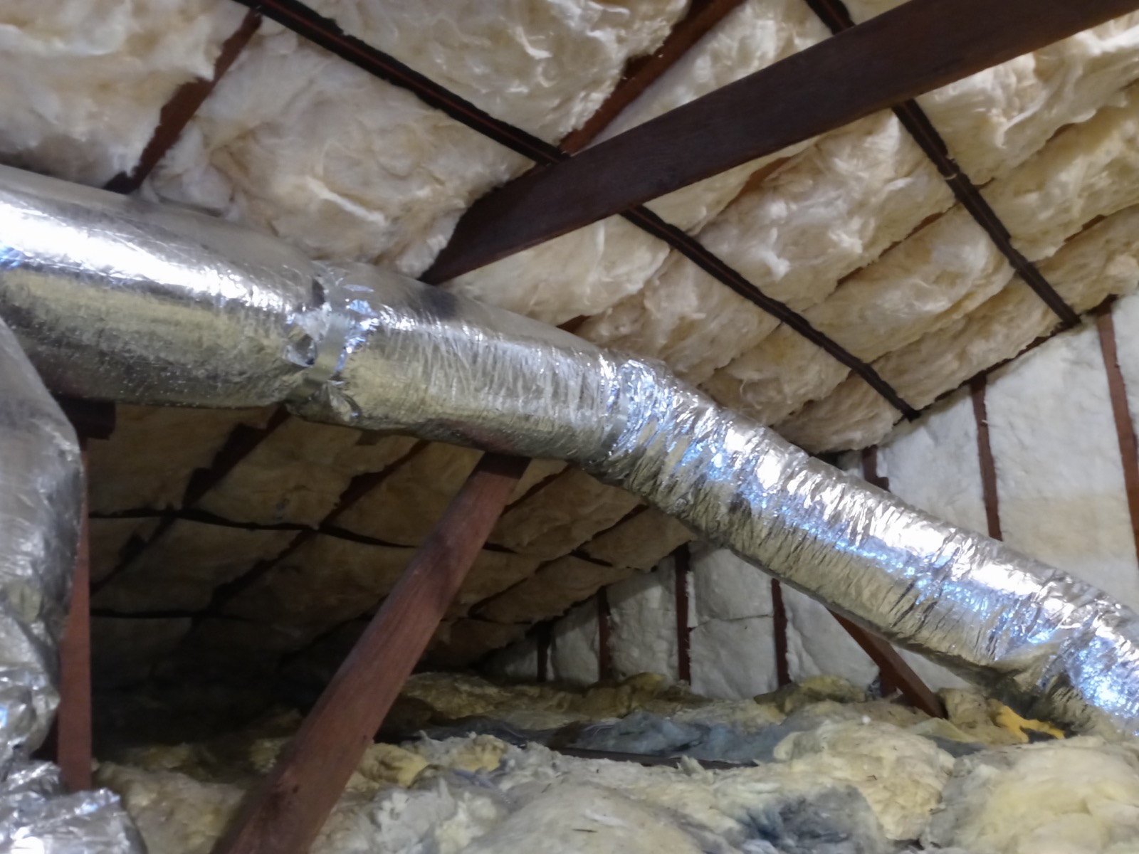 Attic with new fiberglass batt insulation installed to target R-value