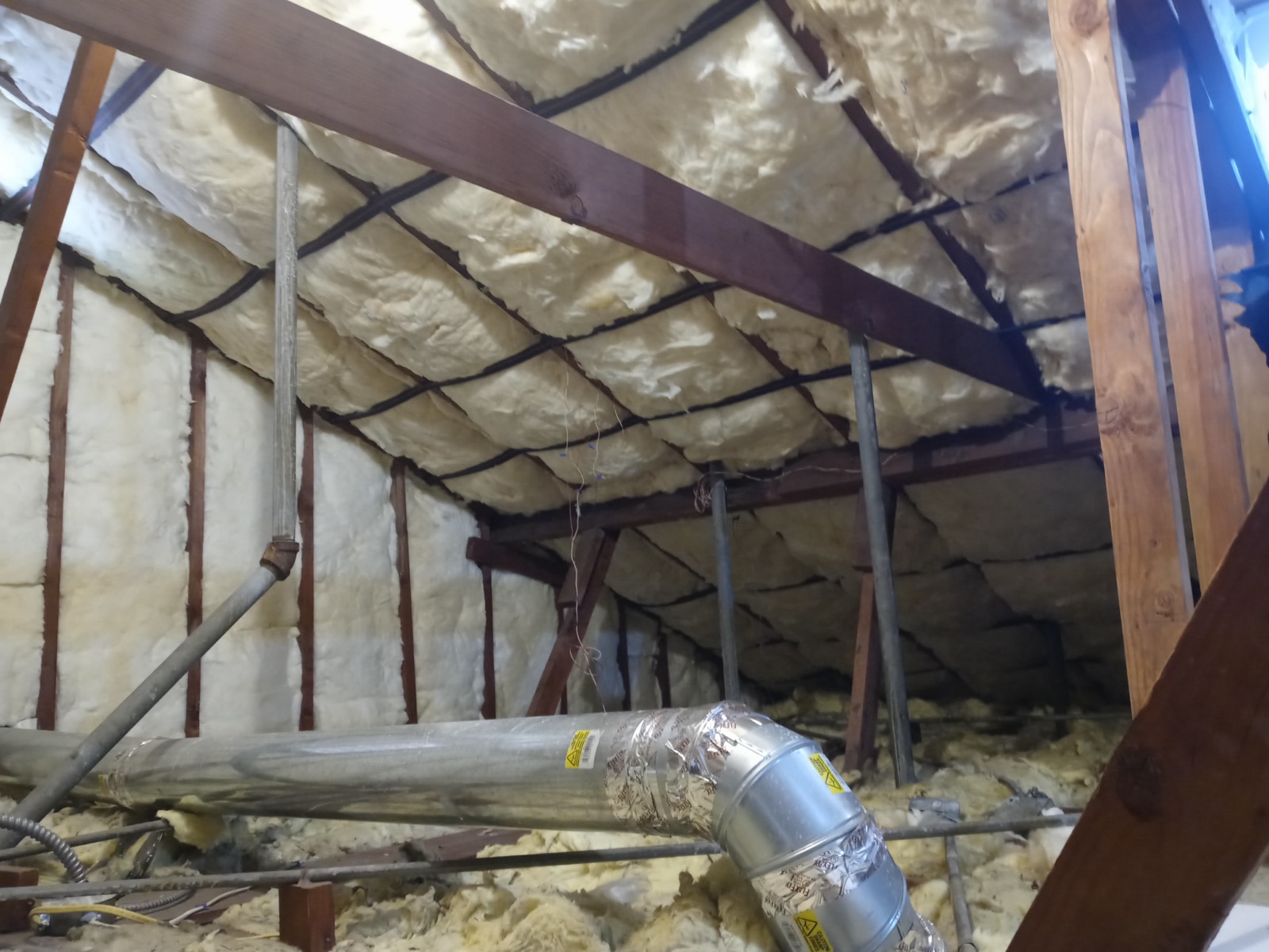 Attic with new fiberglass batt insulation installed to target R-value
