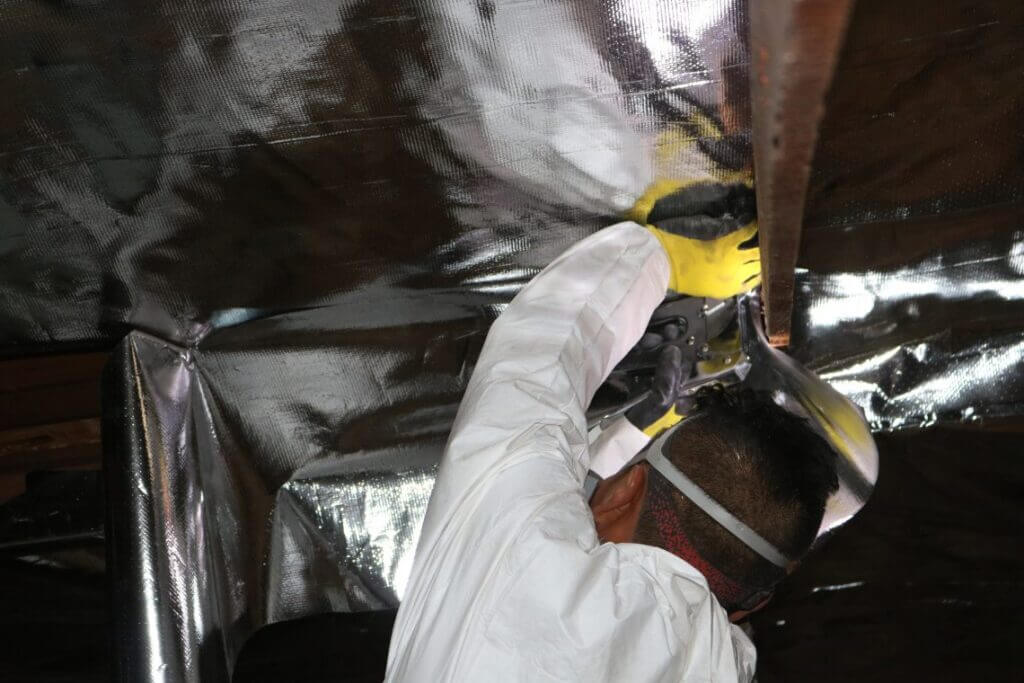Pure Eco technician stapling radiant barrier to attic rafters