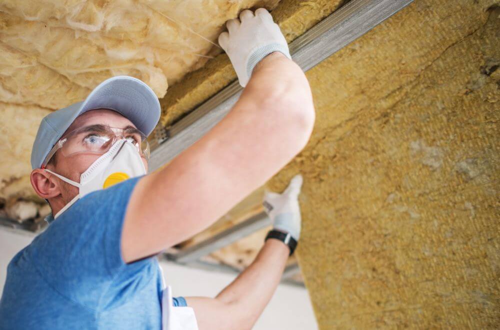 Technician installing crawl space insulation in a Los Angeles home to reduce energy loss
