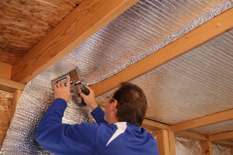 Technician installing crawl space insulation with reflective barrier in a Los Angeles home