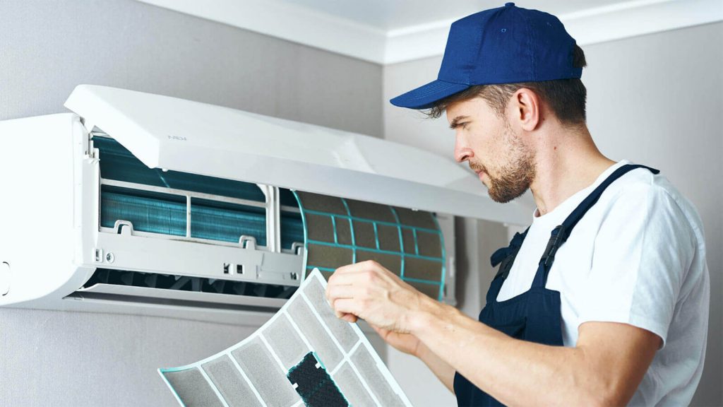 HVAC technician servicing a wall-mounted air conditioner in a Los Angeles home improved by radiant barrier insulation