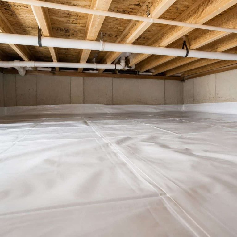 Clean white vapor barrier covering crawl space floor with plumbing pipes above