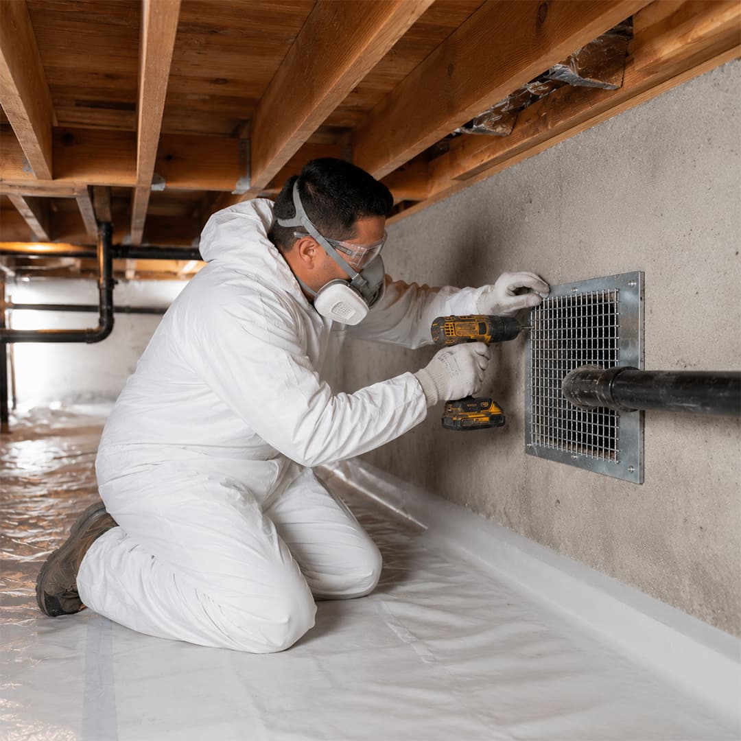 Professional rat proofing technician installing metal mesh over a crawl space vent in Northridge, CA.
