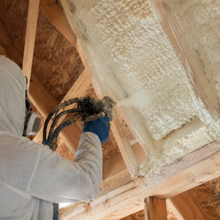 Technician applying spray foam insulation to attic rafters in Chatsworth, CA from a close-up angle.