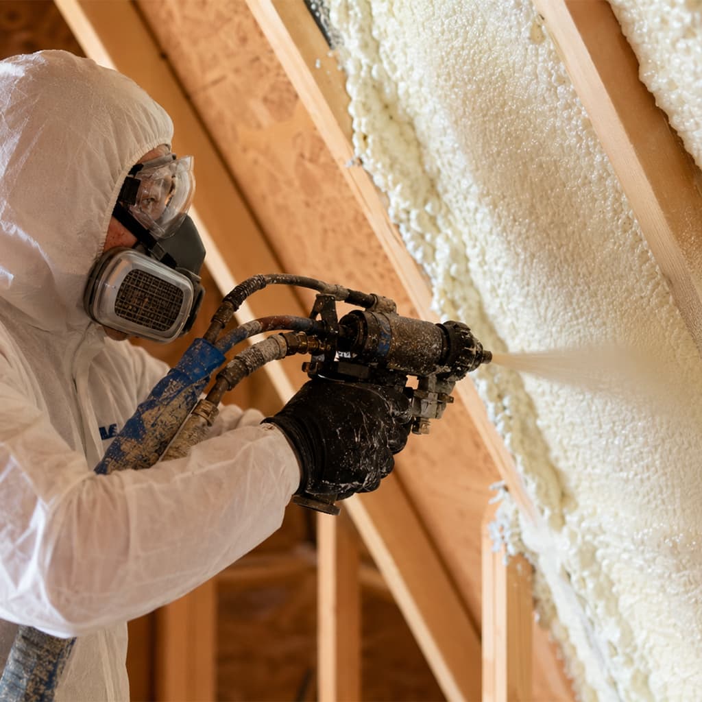 Close-up of a technician applying spray foam insulation inside an attic in Chatsworth, CA.
