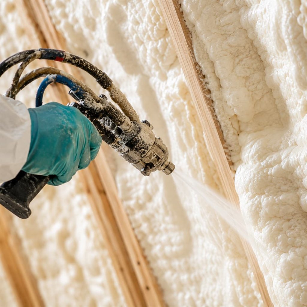 Close-up of a professional technician applying spray foam insulation between attic rafters in Northridge, CA.
