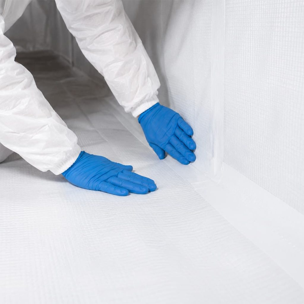 Close-up of a technician smoothing and sealing a white vapor barrier inside a crawl space in Northridge, CA.